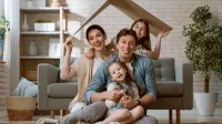 Franke und Bornberg Rating Komposit Wohngebäude - Familie sitzt im Wohnzimmer unter einem spielerischen Papphaus-Dach