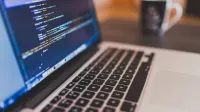 Laptop mit Code auf dem Bildschirm - Deckungsumfang in der Cyber-Versicherung