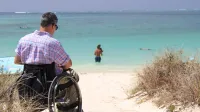 Mann im Rollstuhl am Strand - Grundfähigkeitsversicherung