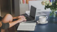 Laptop auf einem Tisch mit zwei Händen die tippen - Rating Private Cyberversicherung