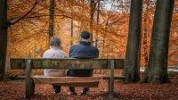 Ein älteres Paar auf einer Parkbank im Herbst - Rentenfaktor-Check 2023